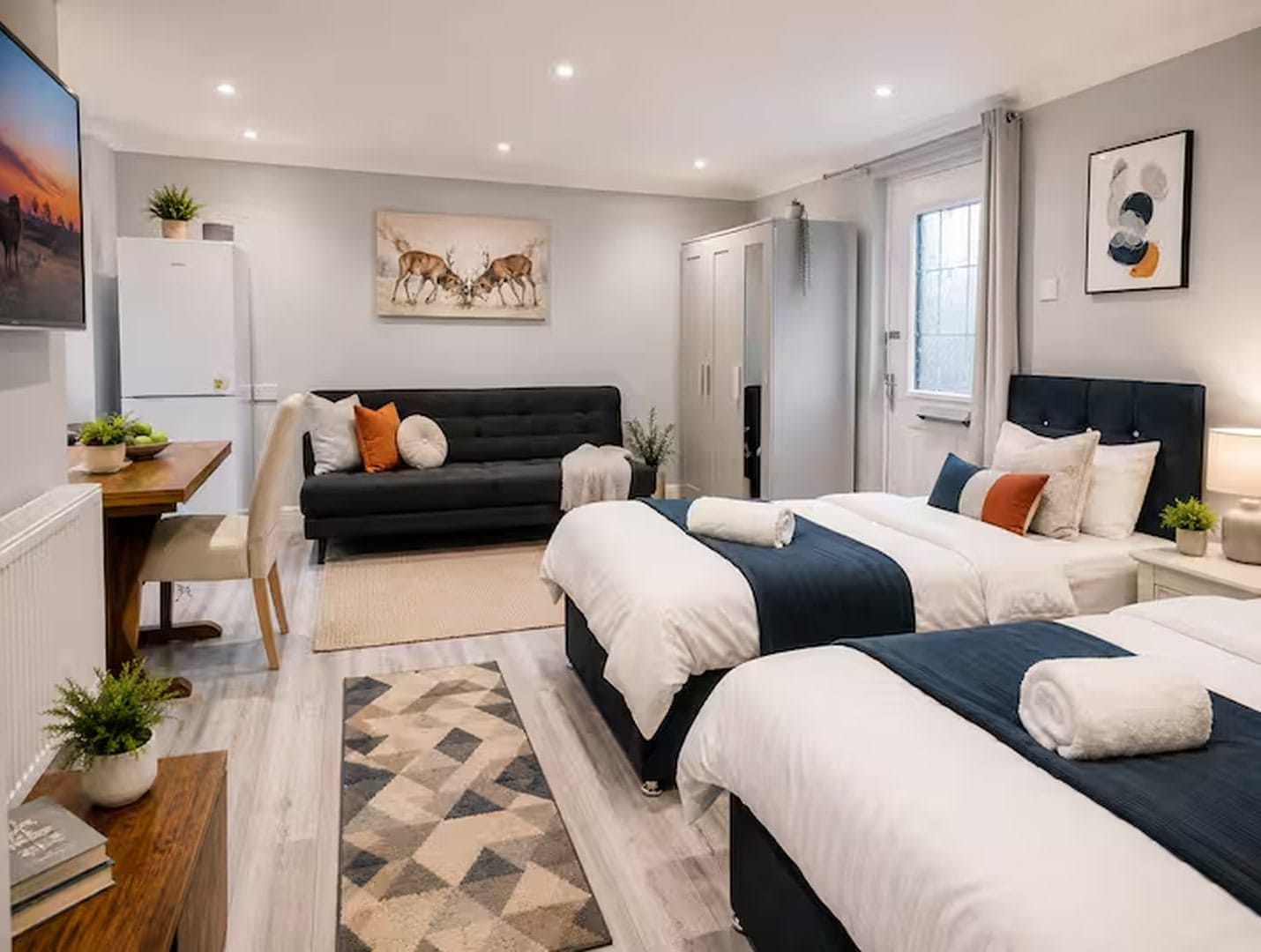 The studio — twin beds, sofa and dining area in a bright, modern room